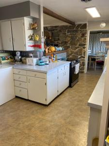 a kitchen with white cabinets and a stone wall at George's B&B in Lewiston