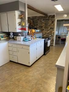 cocina con armarios blancos y pared de piedra en George's B&B en Lewiston