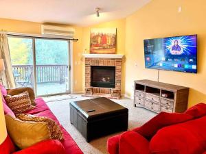 a living room with a red couch and a flat screen tv at Bretton Woods Townhome, Views, 1Gig WiFi, Spacious in Bretton Woods