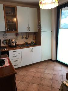a kitchen with white cabinets and a tile floor at appartamenti vacanza El Remanso in Edolo