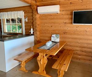 una mesa de madera y un banco en una habitación con TV en Kesäpesä, en Artjärvi