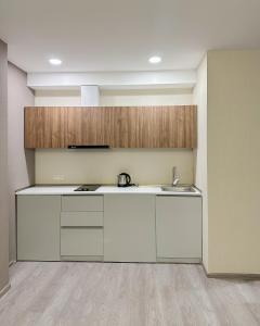 an empty kitchen with white cabinets and a sink at Bakuriani Crystal Loft in Bakuriani