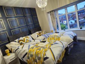 a bedroom with three beds and a chandelier at Clifton House, For Holidays, Contractors, Relocation, Work, Etc, Free Parking and Wifi in Preston