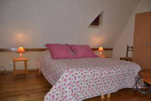 a bedroom with a bed with pink sheets and purple pillows at Maison en pierre 4 couchages in Savignac-de-Miremont