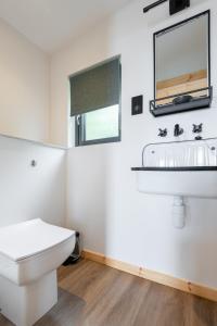 Baño blanco con lavabo y espejo en Rustic Cabins, sea views from rewilded farm, en St Andrews