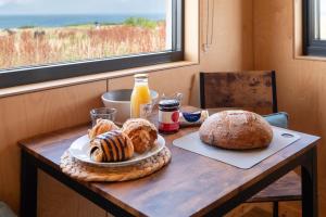 a table with a plate of bread and a bottle of orange juice at Rustic Cabins, sea views from rewilded farm in St. Andrews