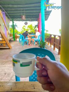 a person holding a coffee cup at a table at El Refugio Minca in Minca