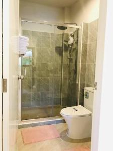 een badkamer met een douche, een toilet en een glazen deur bij Summer House,shared pool, private bathroom and kitchen in Ban Phlu Yai