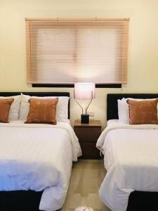 een slaapkamer met 2 bedden en een lamp op een nachtkastje bij Summer House,shared pool, private bathroom and kitchen in Ban Phlu Yai