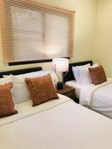 a bedroom with two beds and a lamp and a window at Summer House,shared pool, private bathroom and kitchen in Ban Phlu Yai