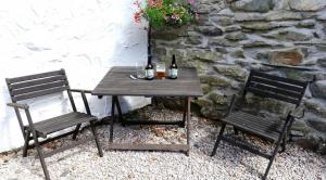 a wooden table with two chairs and two bottles of wine at The Stable, Broughton Beck, near Ulverston in Spark Bridge