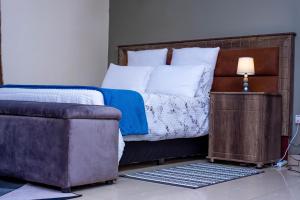 1 dormitorio con 1 cama con silla y sofá en Your home away from home, en Lusaka