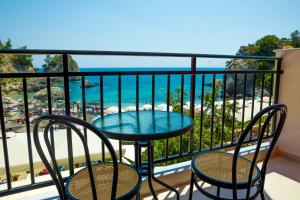 a balcony with a table and chairs and the beach at Golfo Beach in Parga