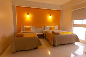 - 2 lits dans une chambre aux murs orange dans l'établissement SC HOTEL, à Xalapa