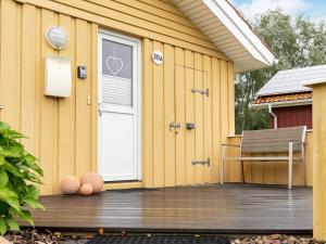 ein gelbes Haus mit einer Tür und einer Bank auf einem Deck in der Unterkunft 4 person holiday home in Otterndorf in Otterndorf