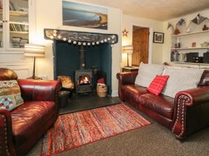 a living room with two leather couches and a fireplace at Bodorwel Cottage in Penrhyndeudreath