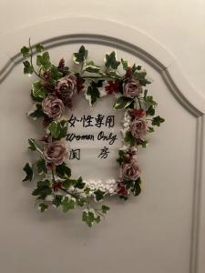 a woman only sign on a wall with flowers at Guest House Tosa Otesujihana Dormitory women only- Vacation STAY 14354 in Kochi