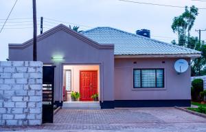 een klein huis met een rode deur bij Your home away from home in Lusaka