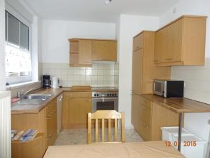 a kitchen with wooden cabinets and a sink and a microwave at Ferienwohnung Freund in Weimar