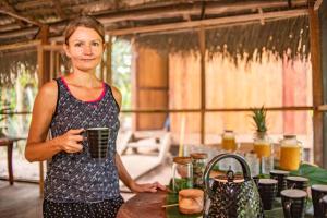 una mujer parada en una cocina sosteniendo una taza en Aparthotel Ayahuaska for SOLO travelers, en Iquitos