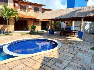 uma piscina em frente a uma casa com um pátio em Chalé das Conchas em Maragogi