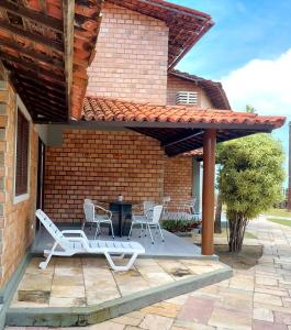 d'une terrasse avec des chaises et une table ainsi que d'un bâtiment en briques. dans l'établissement Chalé das Conchas, à Maragogi