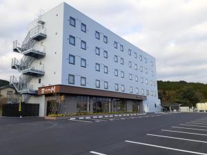 um grande edifício branco com escadas num parque de estacionamento em ＨＯＴＥＬ ＷＩＮ - Vacation STAY 72249v em Imari