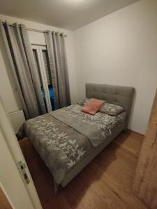 ein kleines Schlafzimmer mit einem Bett mit einer grauen Tagesdecke in der Unterkunft Ada apartman in Banja Luka