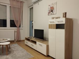 ein Wohnzimmer mit einem Schreibtisch und einem TV in der Unterkunft Ada apartman in Banja Luka