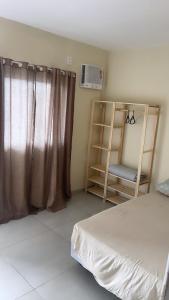 1 dormitorio con cama, ventana y silla en Apartamento Formosa 155, en Cabo Frío