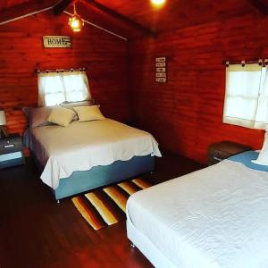 a bedroom with two beds in a wooden cabin at Cabaña campestre #1 in Ráquira