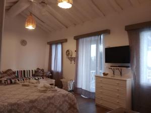a bedroom with a bed and a flat screen tv at Velanidies Traditional Ikarian House in Xilosírtis
