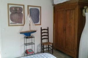 um quarto com uma cama, um armário de madeira e uma cadeira em Bright house with garden - île de Ré em Saint-Clément-des-Baleines