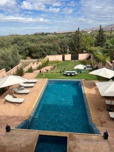 - une vue sur la piscine dotée de chaises longues et de parasols dans l'établissement Riad Timskrine, à Marrakech