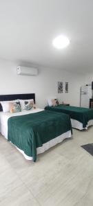 two beds with green sheets in a room at Studio no Bairro Cordeiros in Itajaí