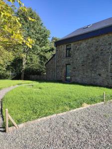 uma casa de tijolos com um quintal relvado ao lado de um edifício em La grange du Moulin em Érezée