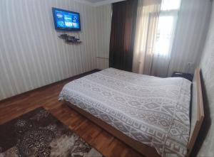 a bedroom with a bed and a tv on the wall at Комфортная квартира для 2х персон in Bishkek +3 photos