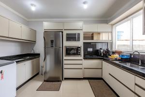 a kitchen with a stainless steel refrigerator and white cabinets at Apartamento 2 quartos com Spá Expocentro Praias in Balneário Camboriú