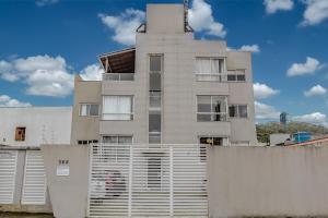 a tall white building with a fence in front of it at Apartamento 2 quartos com Spá Expocentro Praias in Balneário Camboriú
