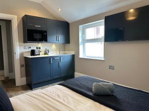 a room with a bed and a kitchen with blue cabinets at Central Studios in Cardiff