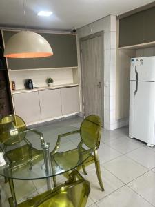 een keuken met een glazen tafel en stoelen en een koelkast bij APARTAMENTO EM EDIFICIO 100% MOBILIADO PARA TEMPORADA in Manaus