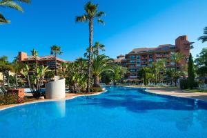 a large swimming pool with palm trees and a hotel at Puerto Antilla Grand Hotel in Islantilla