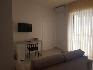 a living room with a couch and a desk with a television at Il Giglio Bianco in Adelfia