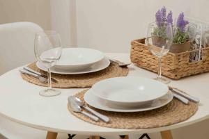 einen weißen Tisch mit 2 Tellern und Weingläsern in der Unterkunft Simplicity Big Apartment in Thessaloniki