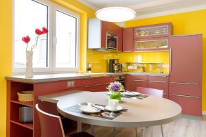 a kitchen with red and yellow walls and a table and chairs at Ferienwohnung Strandläufer in Juliusruh