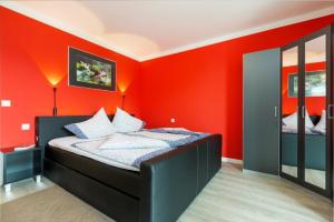 Schlafzimmer mit roten Wänden und einem Bett in der Unterkunft Ferienwohnung Strandläufer in Juliusruh