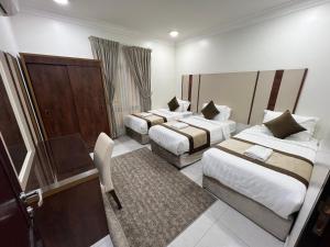 a hotel room with two beds and a desk at ليالي الشرقية لشقق المخدومة in Dammam