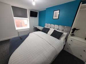 a bedroom with a large bed with a blue wall at Affordable Comfort on Alfreton Road - Ideal for Savvy Travelers in Nottingham