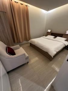 Hotel Apartment -7- L'Avner Al Moteab في الرياض: غرفة نوم بسرير واريكة وكرسي