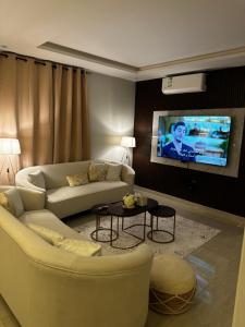 Hotel Apartment -7- L'Avner Al Moteab في الرياض: غرفة معيشة مع أريكة وتلفزيون على الحائط